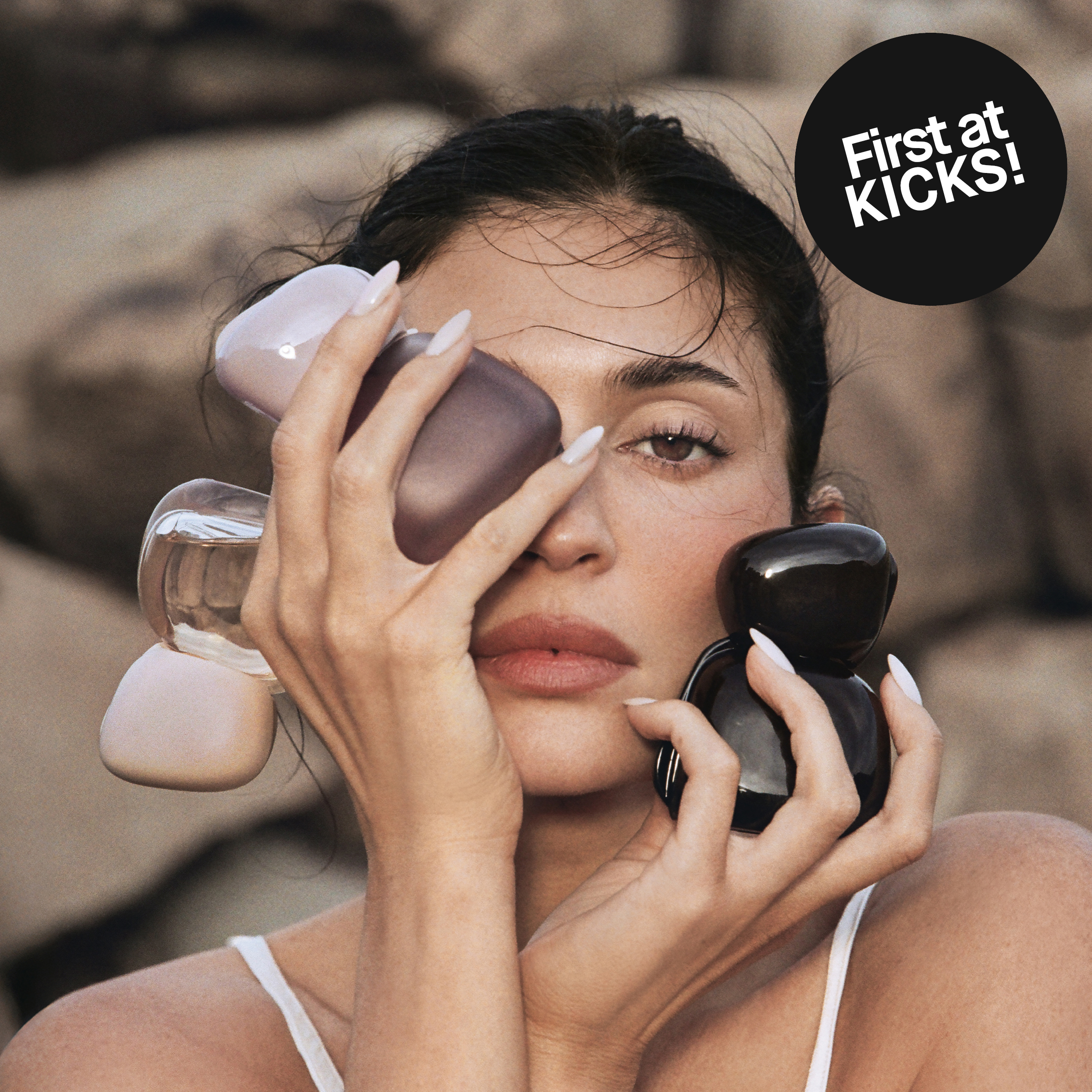 Kvinna håller tre Kylie Cosmetics Mood Stones-parfymflaskor framför ansiktet. Text: ”First at KICKS!”
