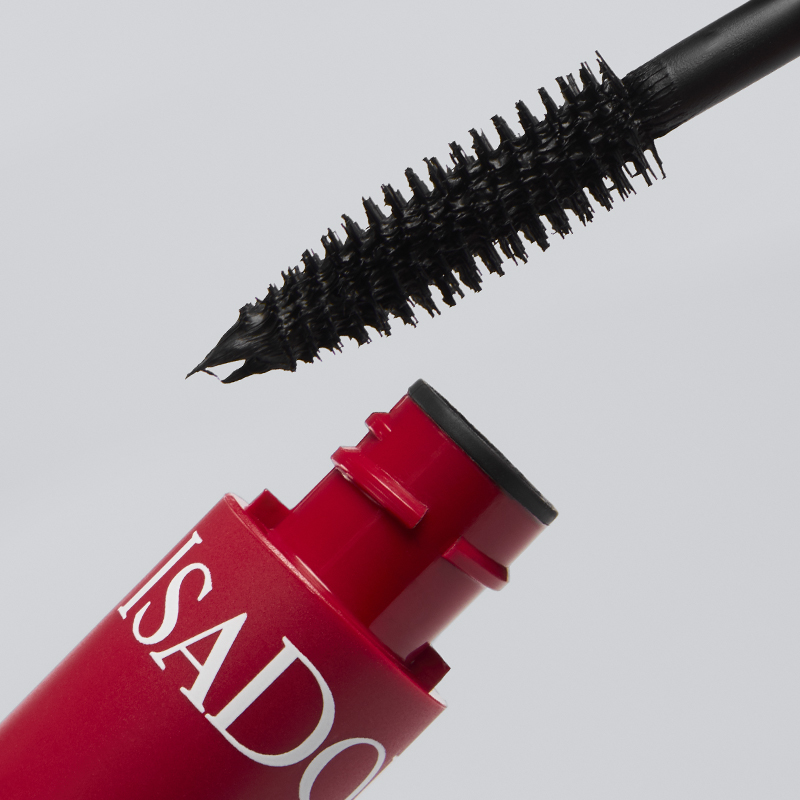 Nærbilde av IsaDora mascara med rød hylse og svart børste med synlig produkt på kosten mot lys bakgrunn. Teksten ISADORA vises på emballasjen.
