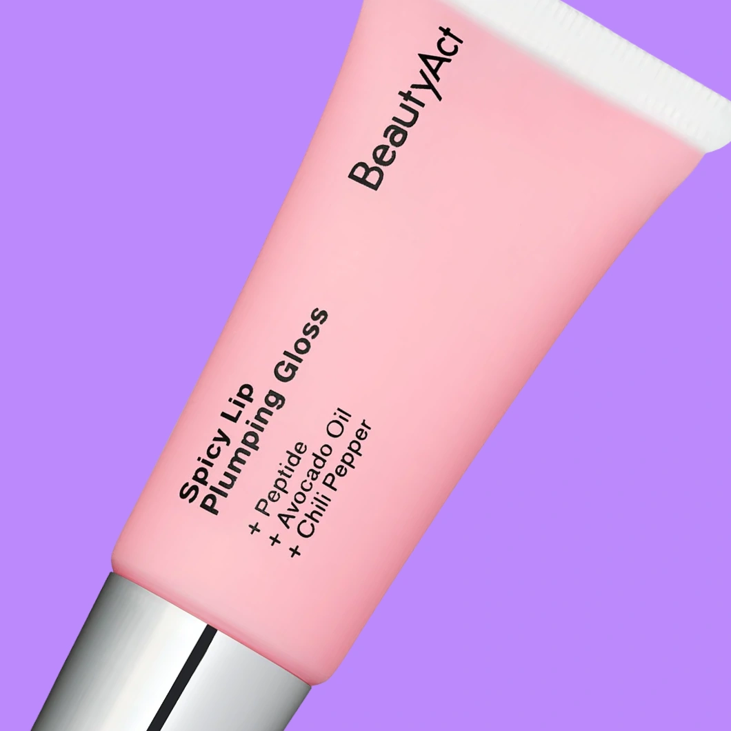 Rosa tub med BeautyAct Spicy Lip Plumping Gloss mot lila bakgrund. På förpackningen står ”BeautyAct”, ”Spicy Lip Plumping Gloss”, ”+ Peptide”, ”+ Avocado Oil” och ”+ Chilli Pepper”.