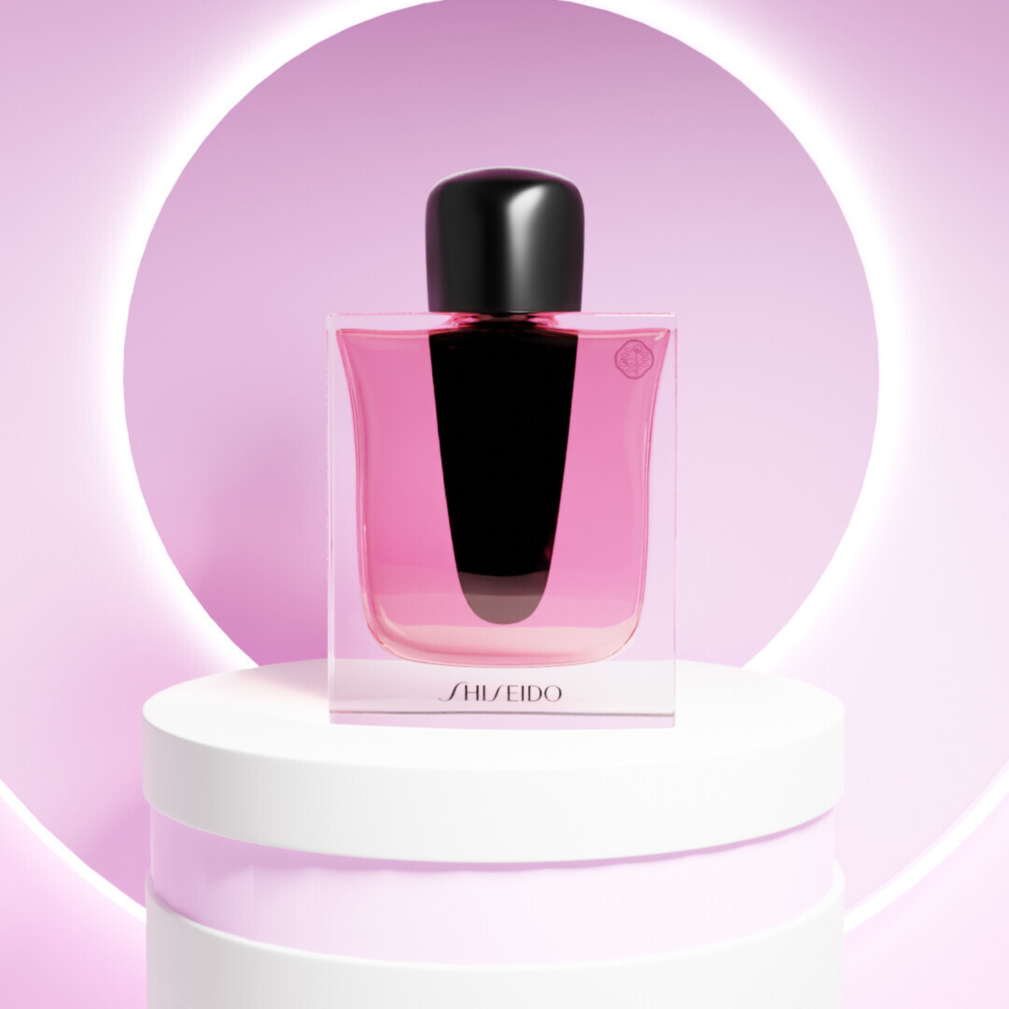 Shiseido parfymeflaske med rosa væske plassert på en sokkel foran en rund lysring.