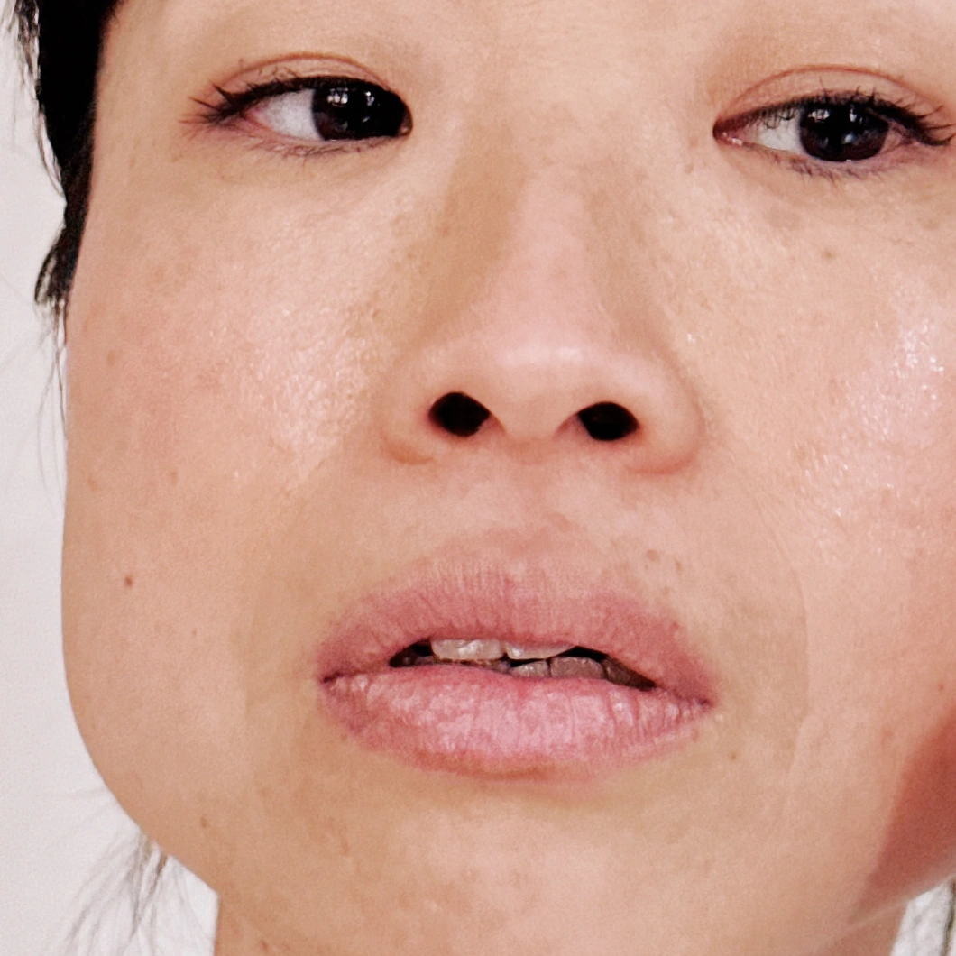 Nærbilde av ansikt med naturlig makeup og fuktet hud, fokus på lepper, nese og øyne med jevn hudstruktur og lett glød som fremhever hudpleie.