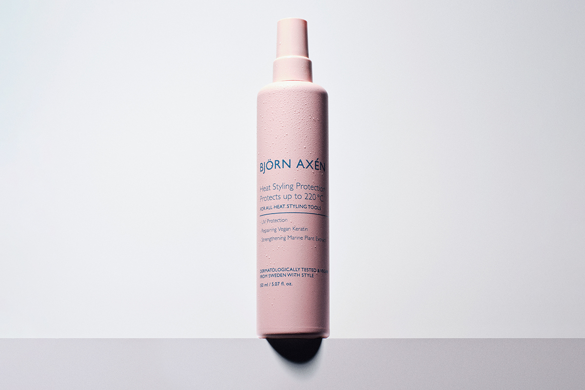 Björn Axéns Heat Styling Protection. Produkten kommer i en rosa sprayflaska. Flaskan står mot en vit bakgrund.