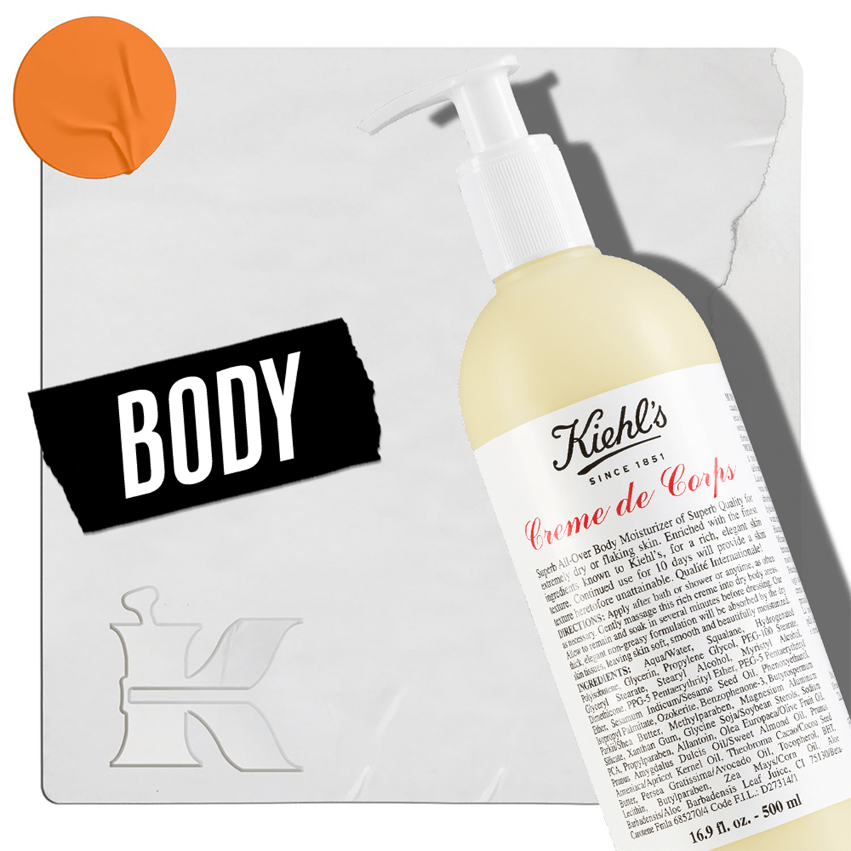 En flaske med Kiehl's Creme de Corps bodylotion med pumpe, plassert mot en lys bakgrunn. I nedre venstre hjørne står teksten «Body» og Kiehl's logo. En oransje sirkel er plassert i øvre venstre hjørne.