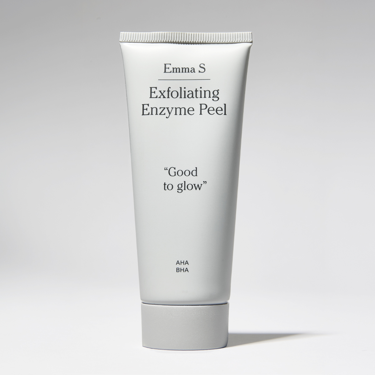 Hvit tube med ansiktspeeling fra Emma S med teksten “Exfoliating Enzyme Peel”, “Good to glow” og “AHA BHA” på en lys bakgrunn.
