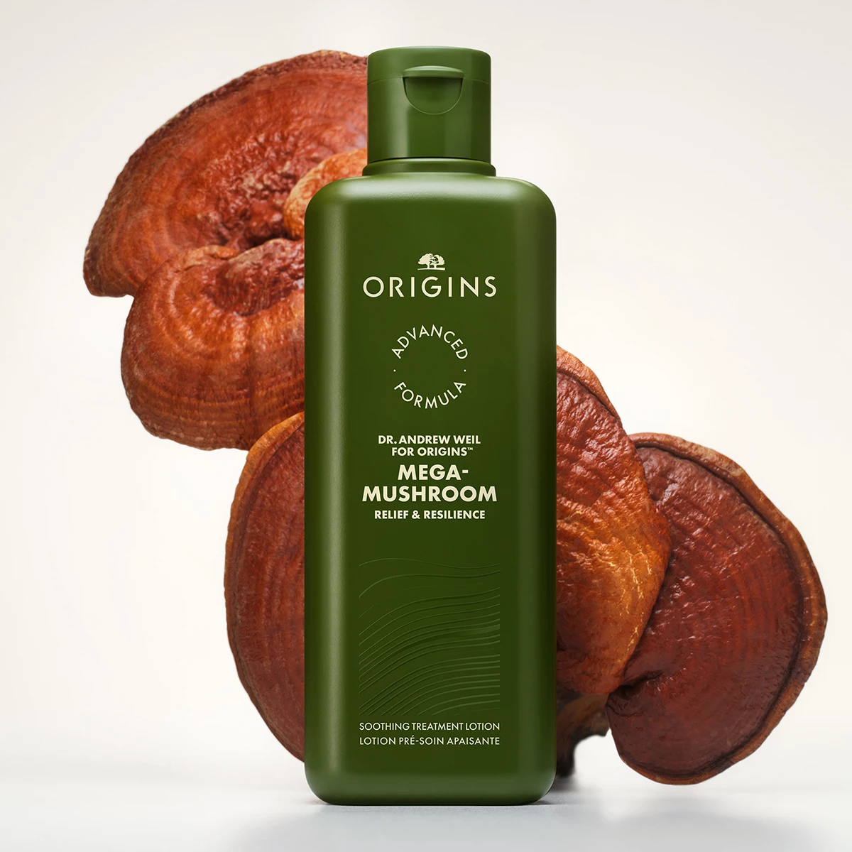 Origins Mega-Mushroom Soothing Treatment Lotion placerad framför stora svampar mot en ljus bakgrund.