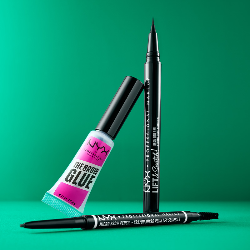 Tre NYX Professional Makeup-produkter mot en grønn bakgrunn. Produktene består av en rosa og blå tube, en svart eyelinerblyant og en svart øyenbrynsblyant.
