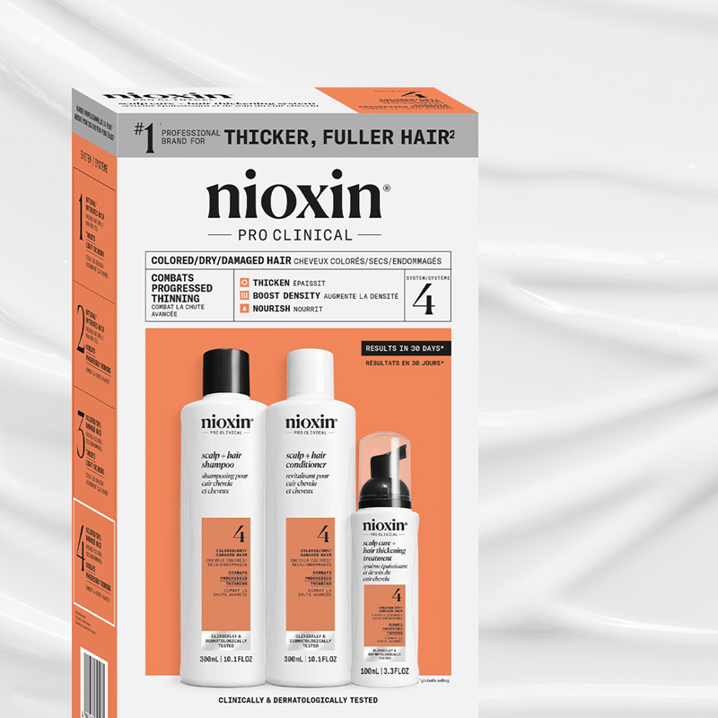 Nioxin Pro Clinical System 4 sett for farget/tørt/skadet hår, med sjampo, balsam og behandling i hvite flasker med oransje etiketter.