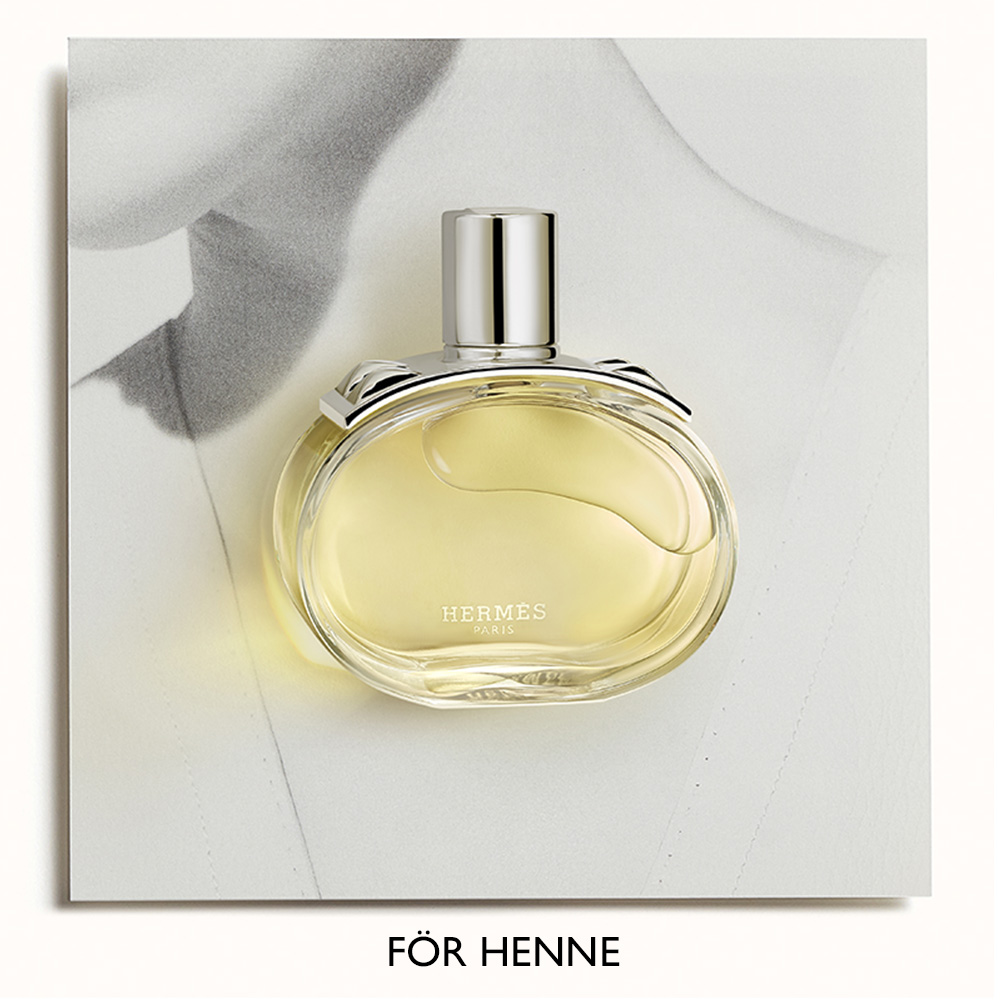 "FÖR HENNE". Parfymflaska från Hermès, med en ljusgul vätska, placerad framför en svartvit bild av en kvinnas överkropp.
