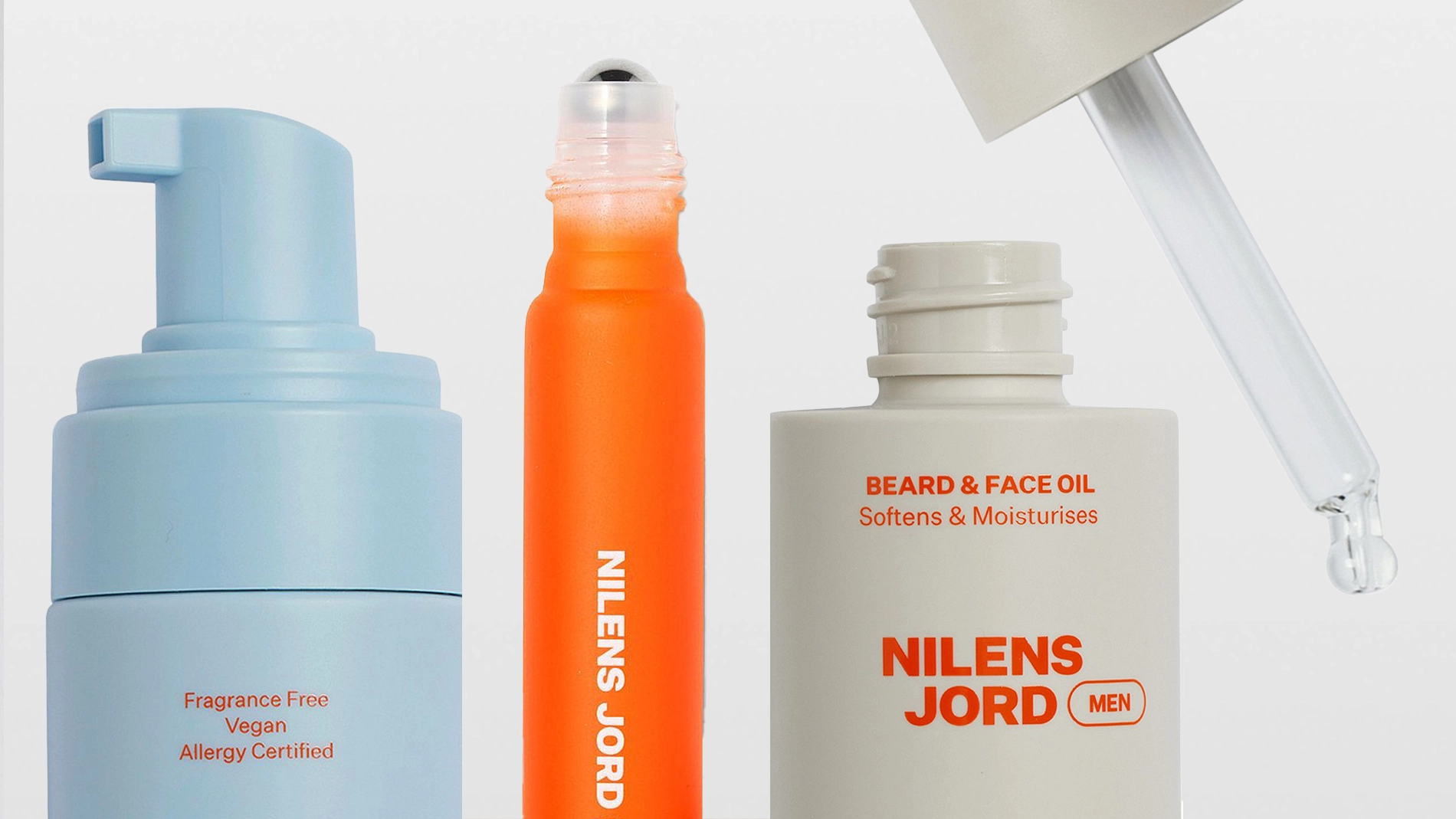 Nilens Jord MEN -ihonhoito- ja groomingtuotteita vaaleaa taustaa vasten, mukana vaahtoputsari, roll-on-tuote ja Beard & Face Oil -öljy pipetillä. Pakkauksissa näkyvät tekstit “Fragrance Free”, “Vegan”, “Allergy Certified”, “BEARD & FACE OIL Softens & Moisturises” ja “NILENS JORD MEN”.