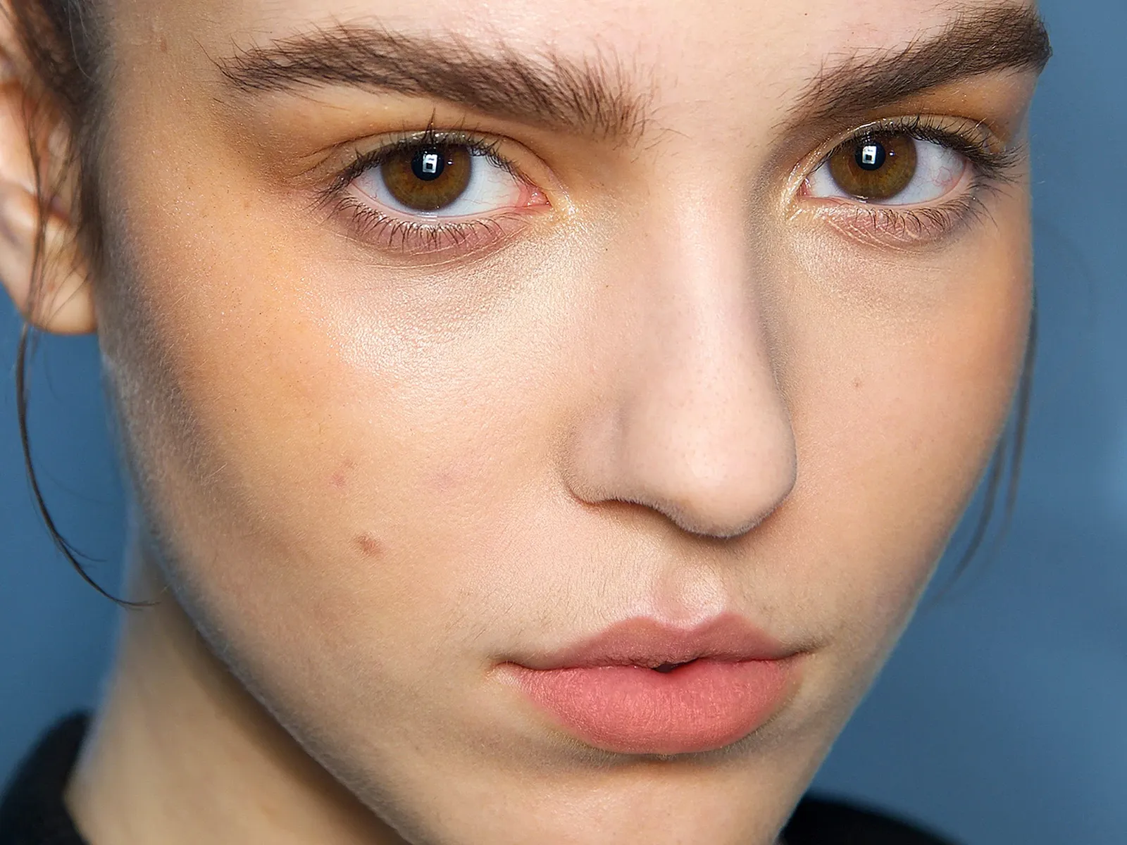 Närbild på ett ansikte med naturlig makeup och välformade ögonbryn.
