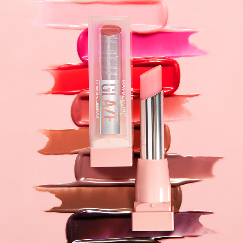 Maybelline leppeprodukt og emballasje mot rosa bakgrunn, med utstrøkne leppefarger rundt.