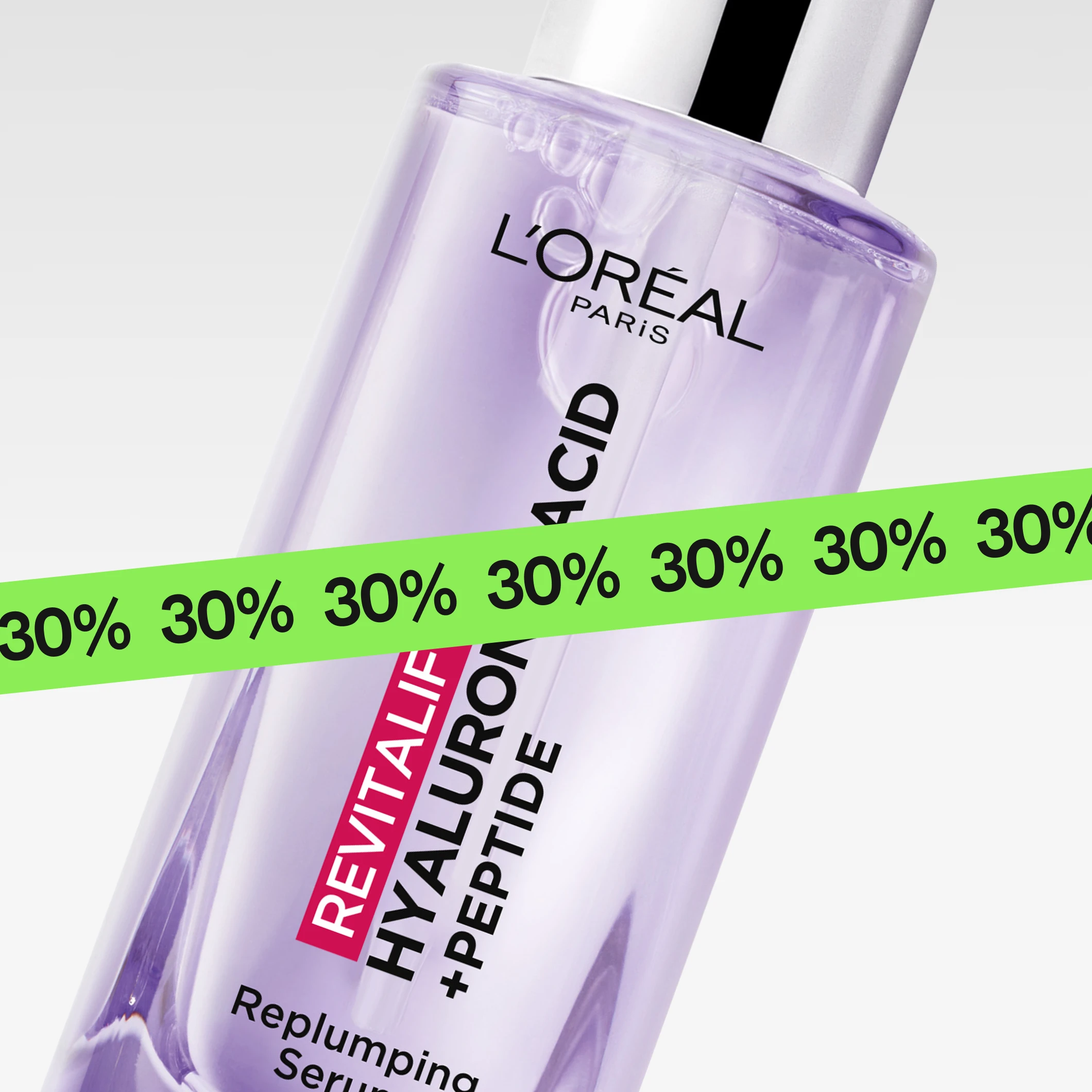 Nærbilde av hudpleieserum “L’Oréal Paris Revitalift Hyaluronic Acid + Peptide Replumping Serum” i lilla flaske, delvis dekket av en grønn banner med gjentatt “30%”.