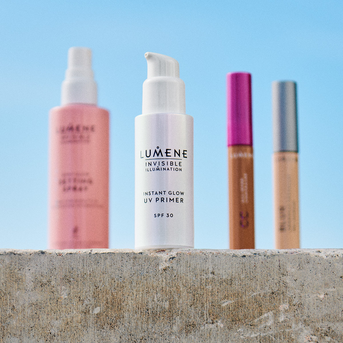 Fire Lumene hudpleieprodukter på en betongoverflate utendørs. Setting spray, UV primer, CC cream og concealer.