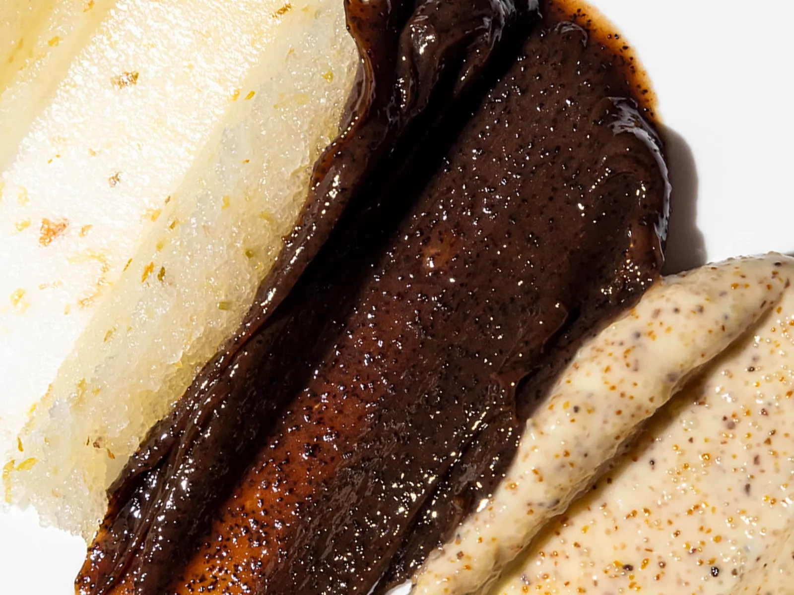 Närbild av tre olika ansiktsskrubbar i varierande färger och texturer