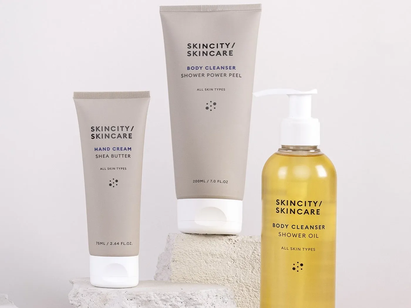 Tre produkter från Skincity Skincare placerade på stenar, mot en grå bakgrund.