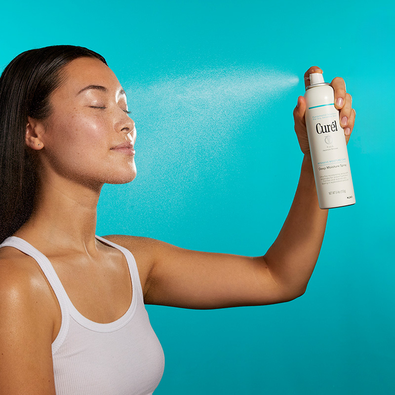 Kvinne sprayer Curél-fuktighetsspray i ansiktet.
