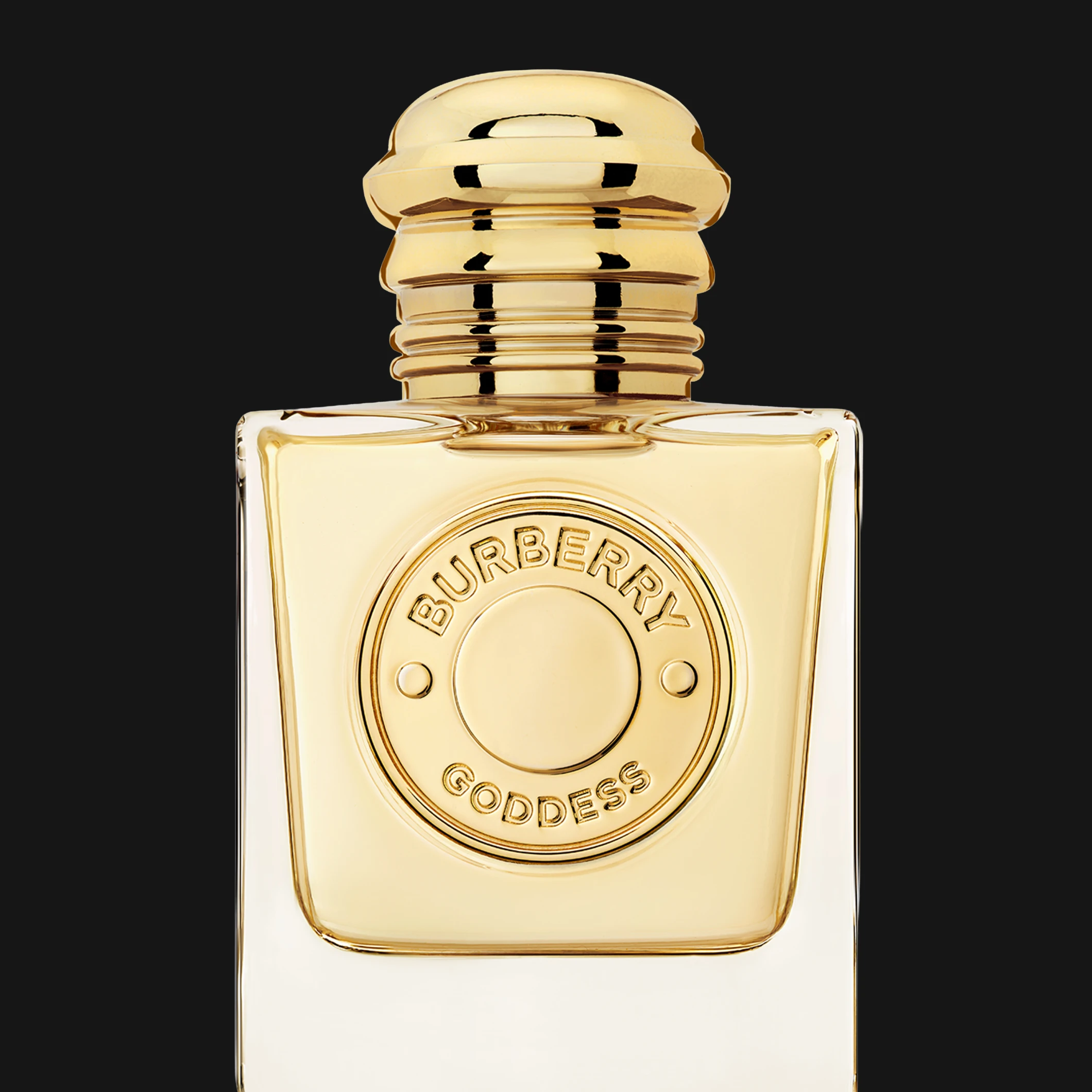 Burberry Goddess parfymflaska i glas med guldfärgad kork och rund guldfärgad emblemdekor med texten ”BURBERRY GODDESS”. Produkten visas mot svart bakgrund.