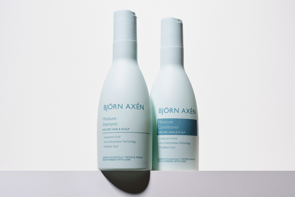 Björn Axéns Moisture Shampoo och Moisture Conditioner. Båda produkterna kommer i ljusblå flaskor. Flaskorna står bredvid varandra mot en vit bakgrund.
