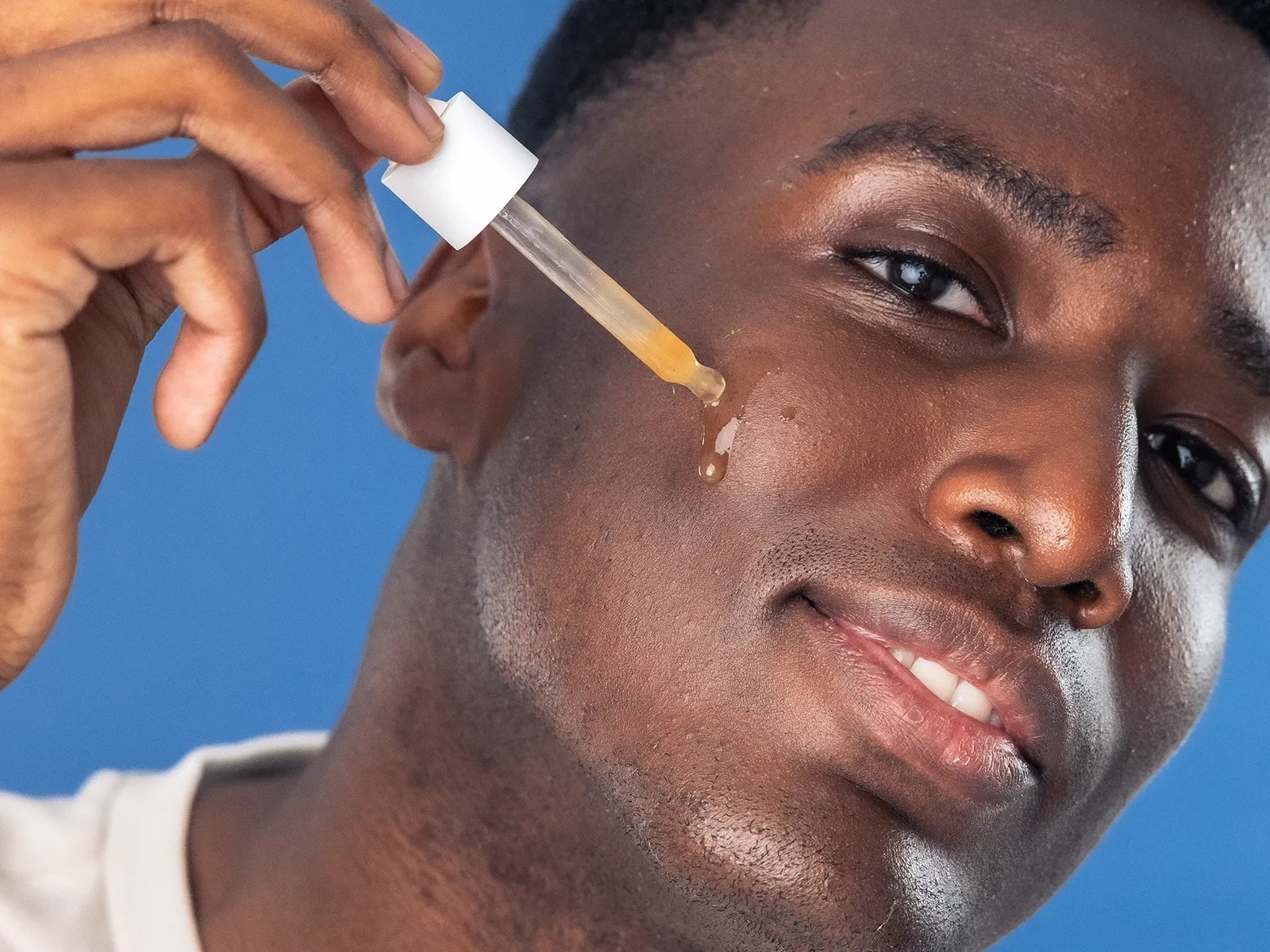 En person påfører en hudpleieprodukt på kinnet med en pipette.