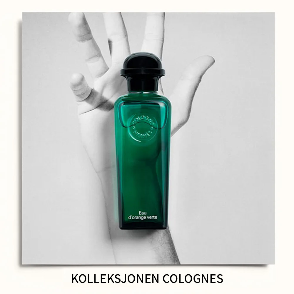 «Kolleksjonen Colognes». Parfymeflasken Hermès Eau d’Orange Verte plassert foran et svart-hvitt bilde av en hånd.