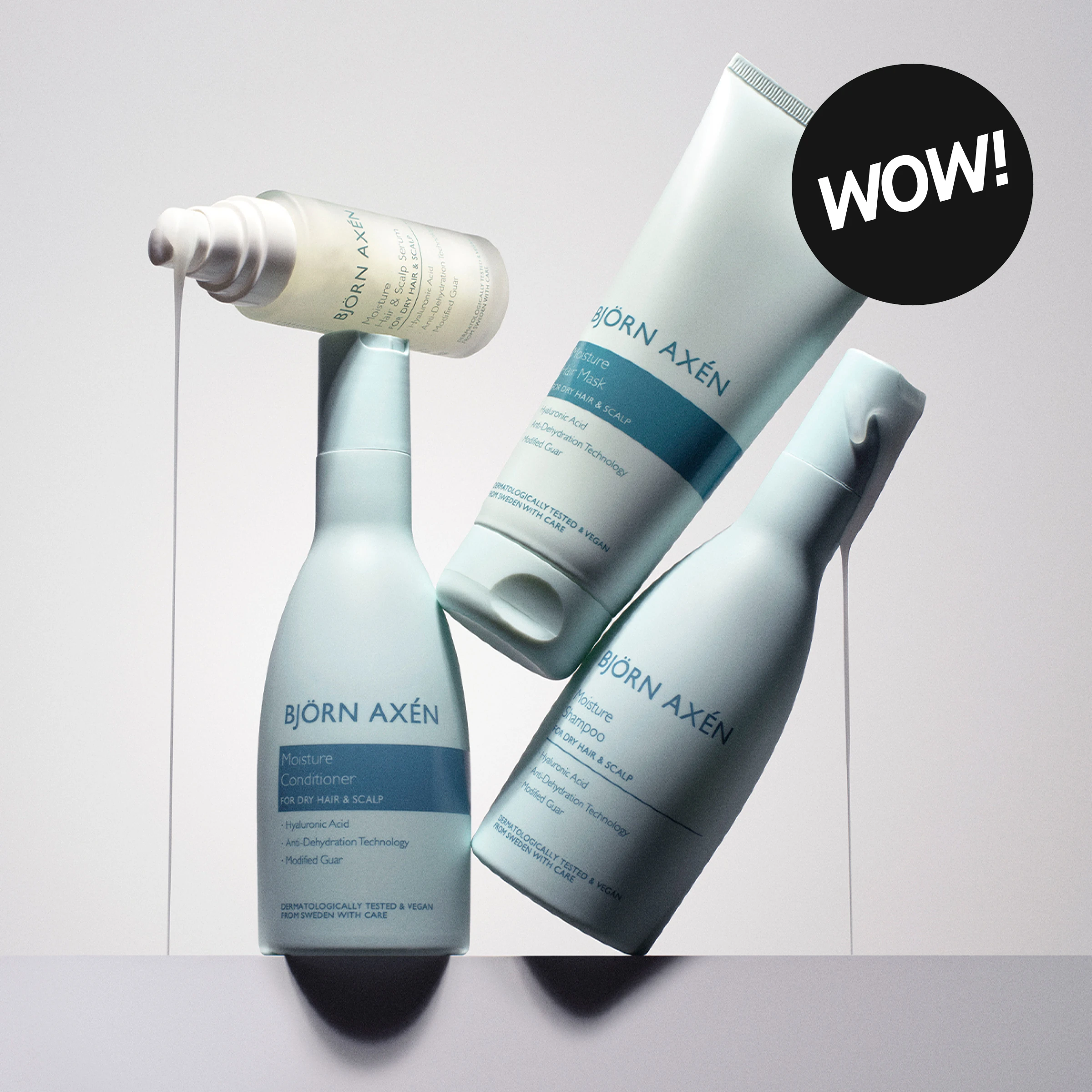 Björn Axén Moisture-hårvårdsprodukter mot ljus bakgrund med texten ”BJÖRN AXÉN” synlig på förpackningarna. Produkterna inkluderar Moisture Conditioner, Moisture Hair & Scalp Serum, Moisture Hair Mask och Moisture Shampoo, och en svart cirkel med texten ”WOW!” visas i bilden.