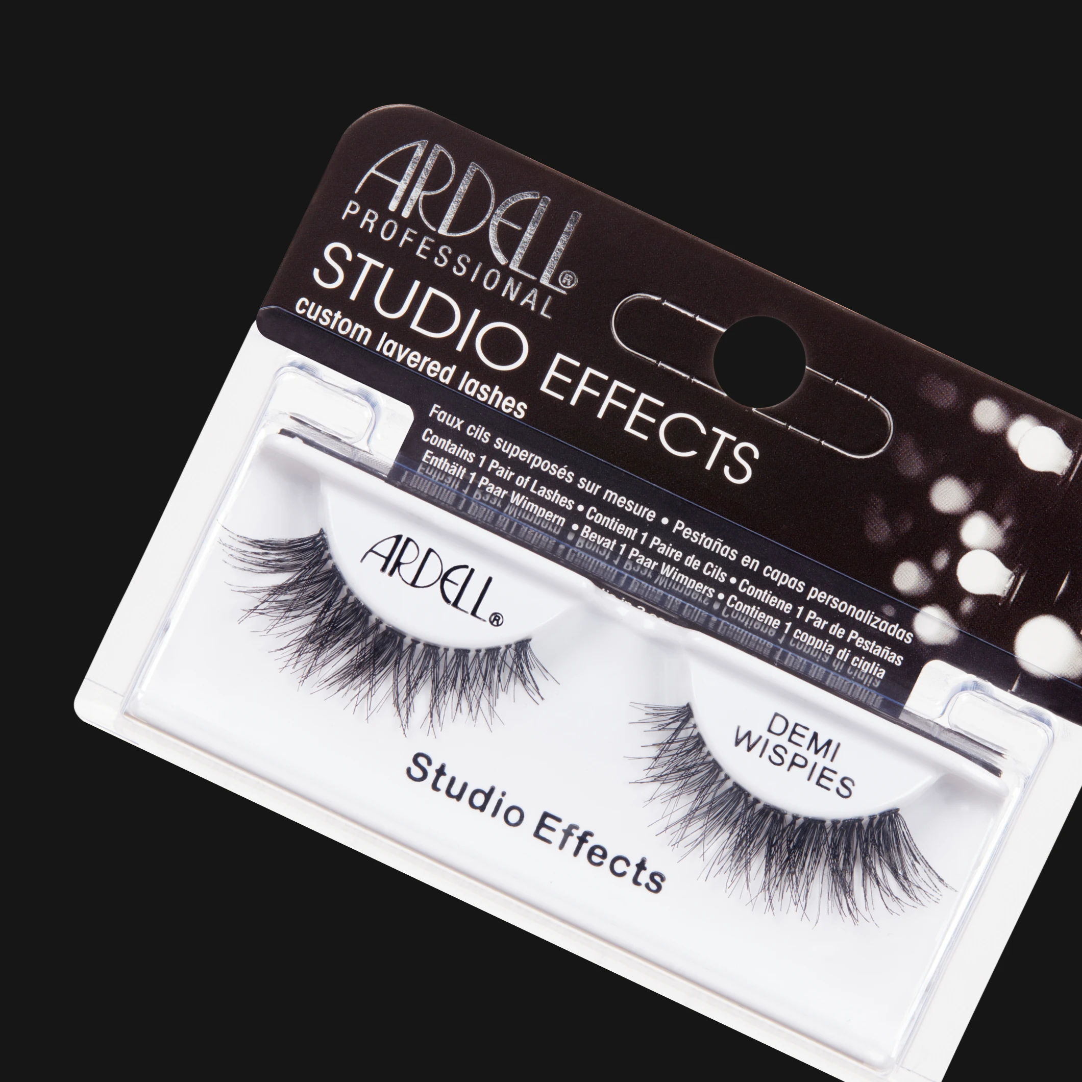 Ardell Professional Studio Effects Demi Wispies lösögonfransar i transparent förpackning mot svart bakgrund. På förpackningen syns texterna ”ARDELL PROFESSIONAL”, ”STUDIO EFFECTS”, ”custom layered lashes”, ”Studio Effects” och ”DEMI WISPIES”.