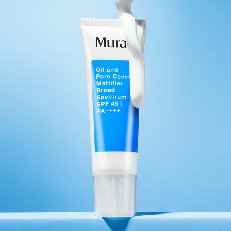 Ansiktskräm från Murad placerad mot en ljusblå bakgrund. Tuben är vit med en blå etikett som visar produktnamnet. En vit kräm appliceras på toppen av tuben, vilket framhäver produktens konsistens och dess solskyddande egenskaper.