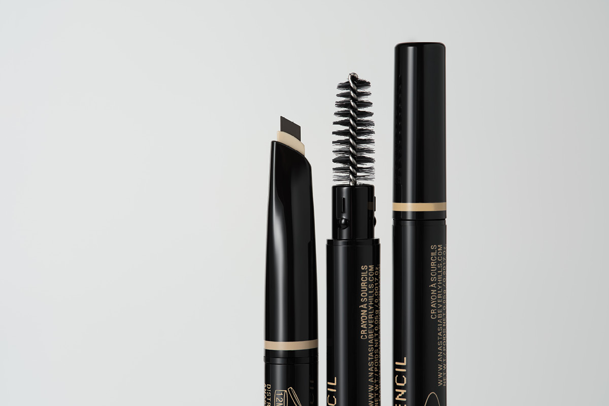 Två svarta ögonbrynsprodukter med borste och sned spets mot ljus bakgrund.
