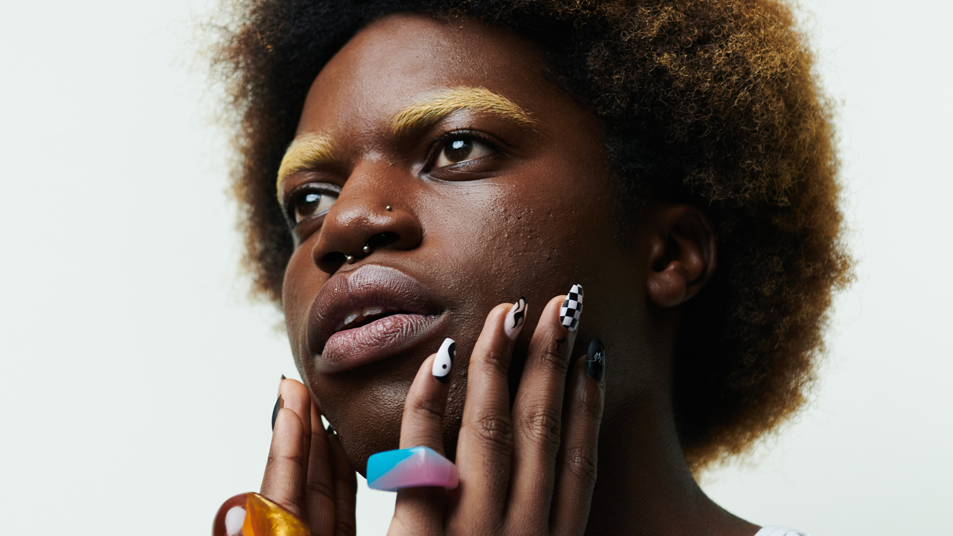 Henkilö, jolla on afro-kampaus ja värikkäitä sormuksia sormissaan.