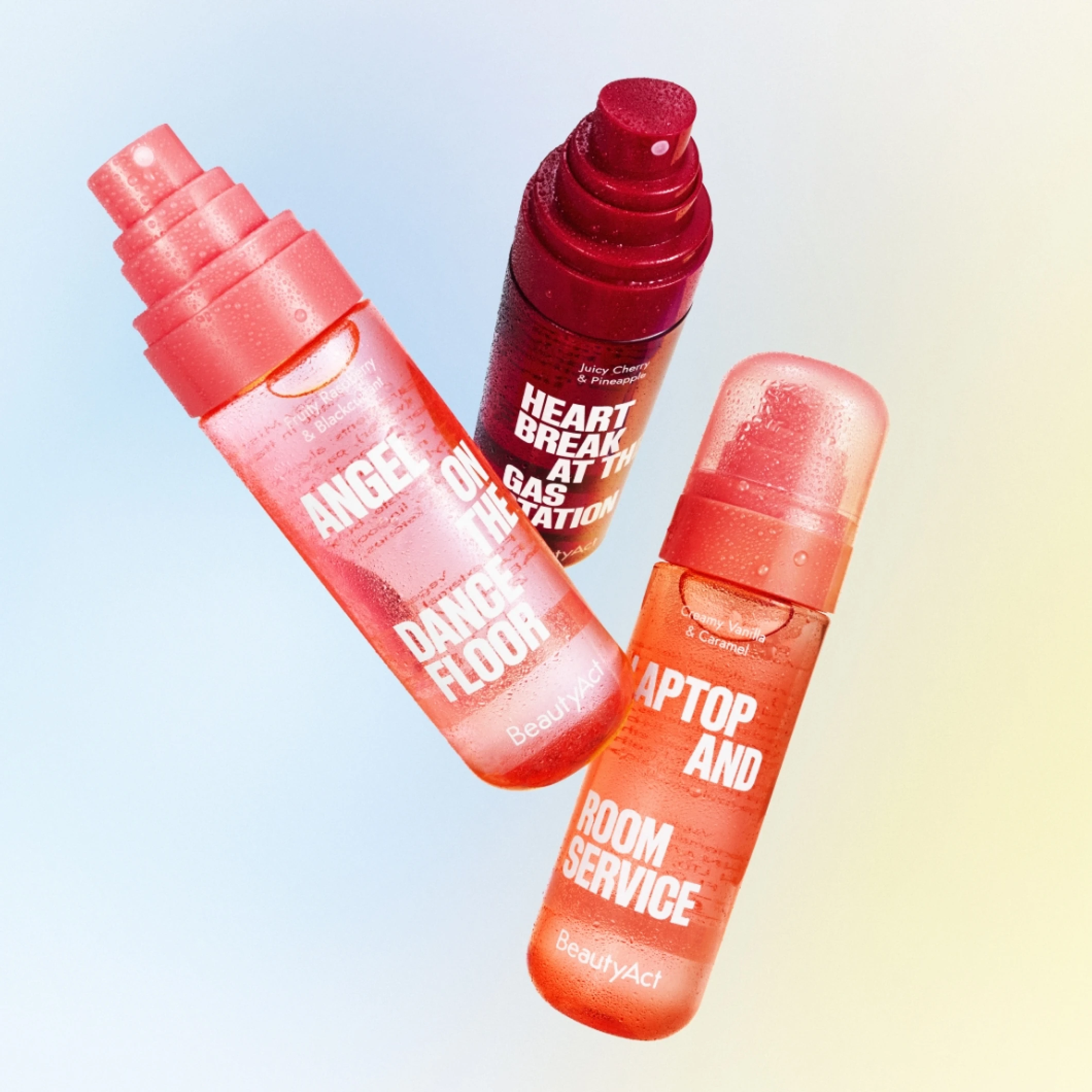BeautyAct-bodymists mot rosa og blå bakgrunn. Bildet viser produktene «Angel on the Dance Floor», «Heart Break at the Gas Station» og «Laptop and Room Service».