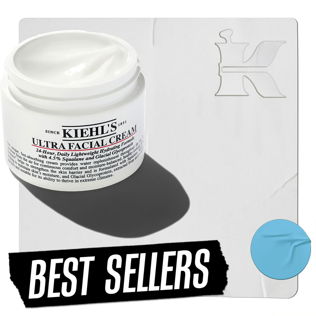 En krukke med Kiehl's Ultra Facial Cream plassert mot en lys bakgrunn. I nedre venstre hjørne er teksten «Best Sellers», og i øvre høyre hjørne er Kiehl's-logoen. En blå sirkel er plassert nederst i høyre hjørne.