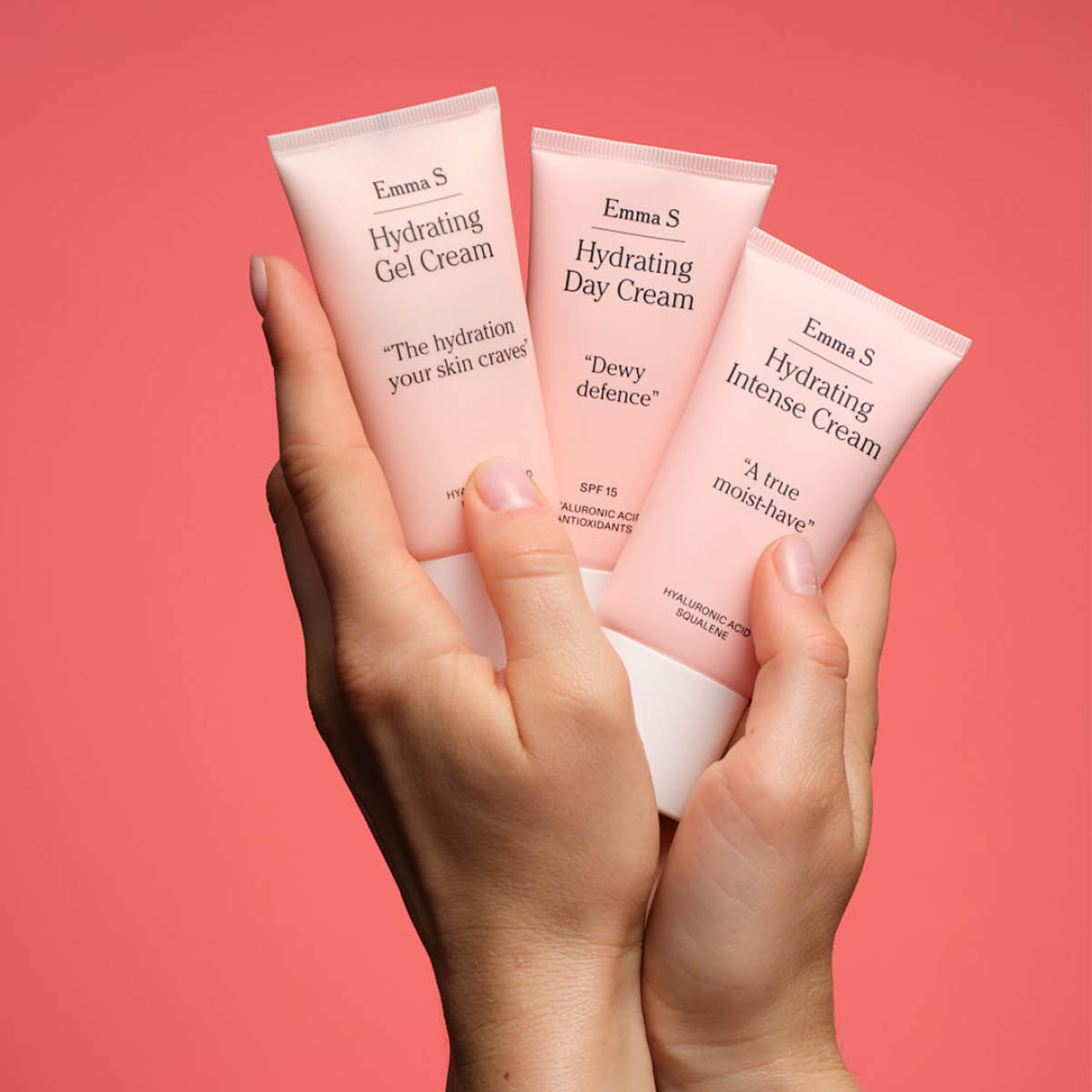 Hender holder tre fuktighetskremer fra Emma S i rosa tuber. Kremene heter Hydrating Gel Cream, Hydrating Day Cream og Hydrating Intense Cream.