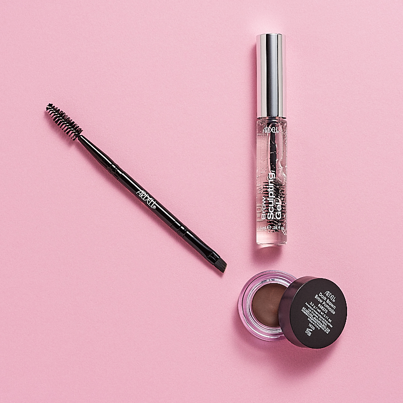 Ögonbrynsprodukter från Ardell, inklusive en ögonbrynspenna med borste, Brow Sculpting Gel och Brow Pomade. Produkterna är placerade på en rosa bakgrund.