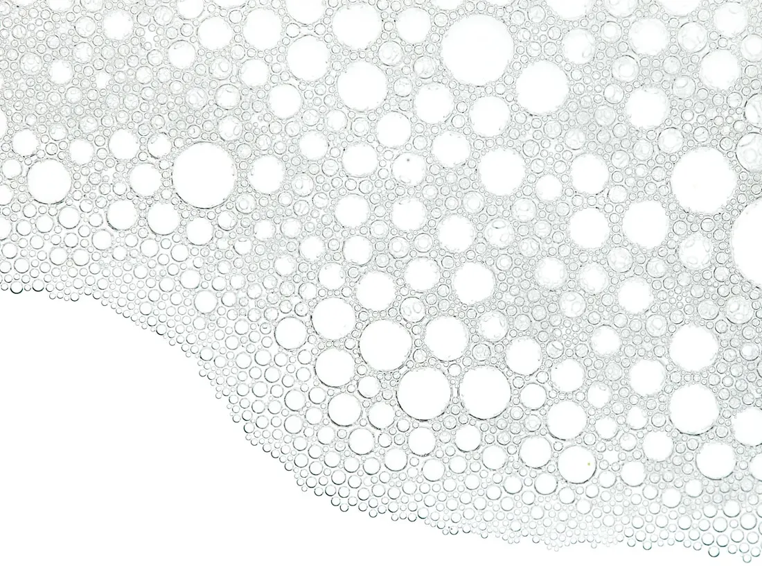 Ostrukturerade bubblor i olika storlekar mot en vit bakgrund.