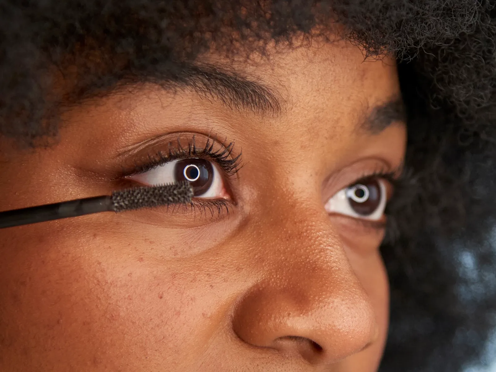 Närbild på en person som applicerar mascara på sina ögonfransar