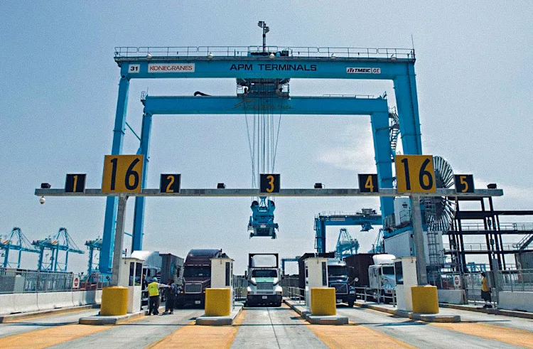 APM Terminals gate with trucks ready for container handling, showcasing efficient logistics and coordination under the management of large cranes for streamlined port operations.