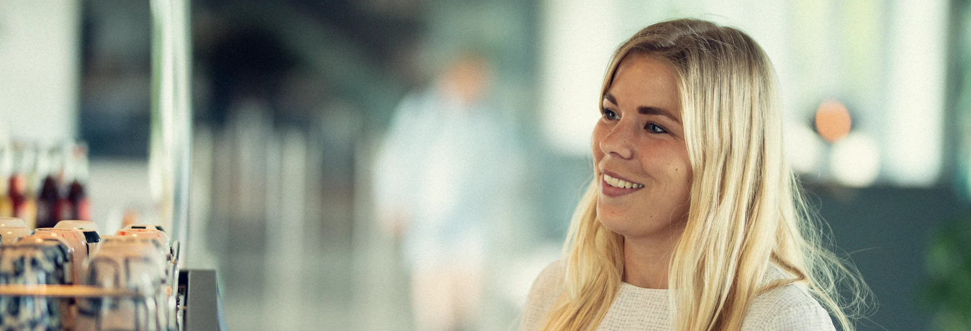 woman standing at what appears to be a counter, smiling and engaged in a friendly interaction.