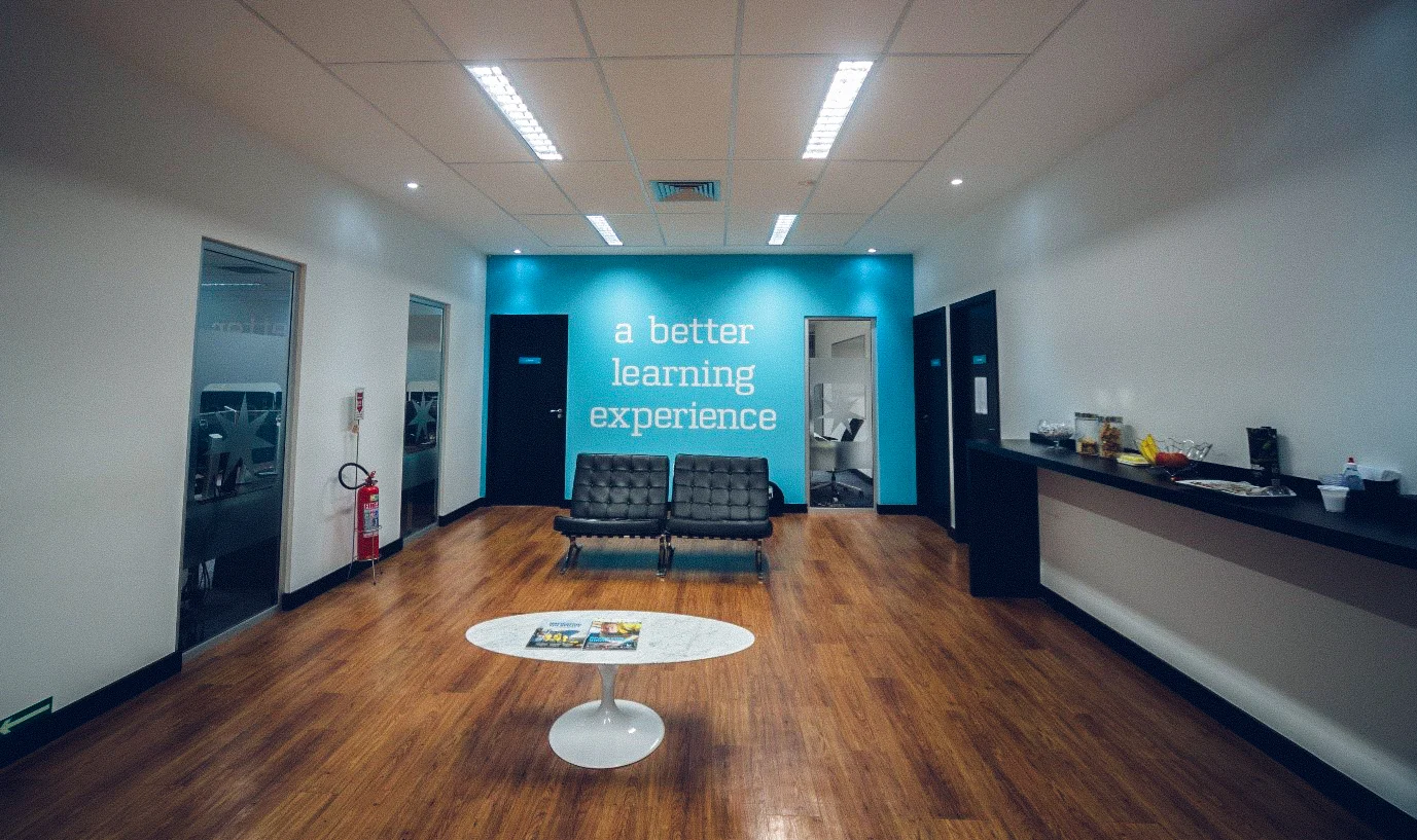 A welcoming lounge area in a training facility, featuring comfortable seating and a bold wall message, "a better learning experience," fostering a positive and engaging atmosphere for learners.