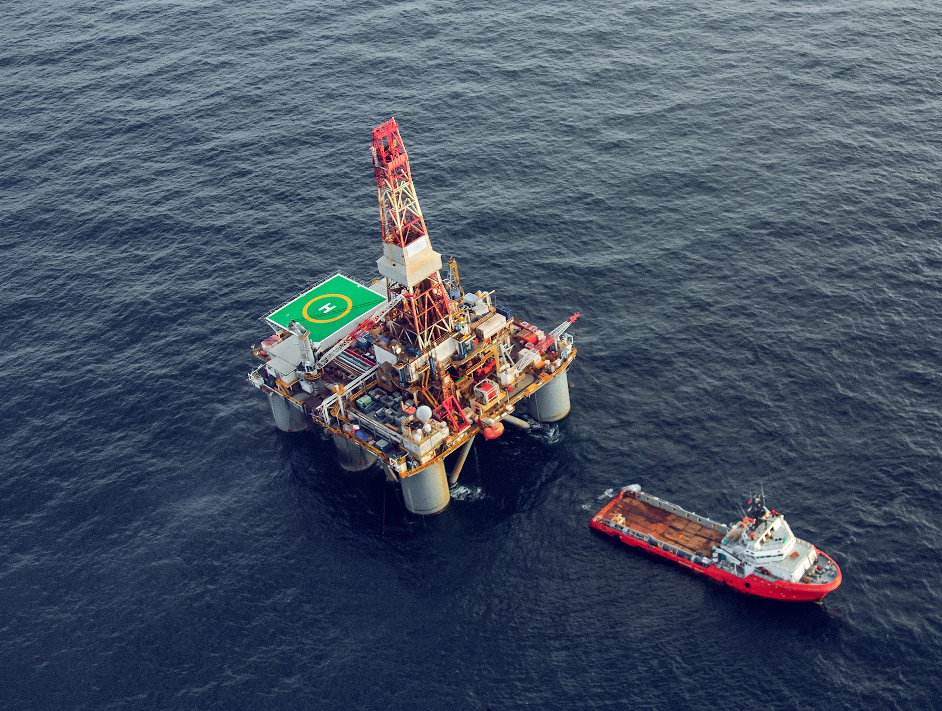semi-sub oil rig with a large support boat nearby
