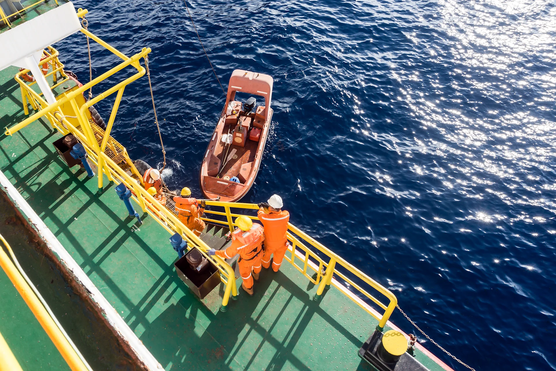 Fast rescue craft being deployed from a construction barge at oil field