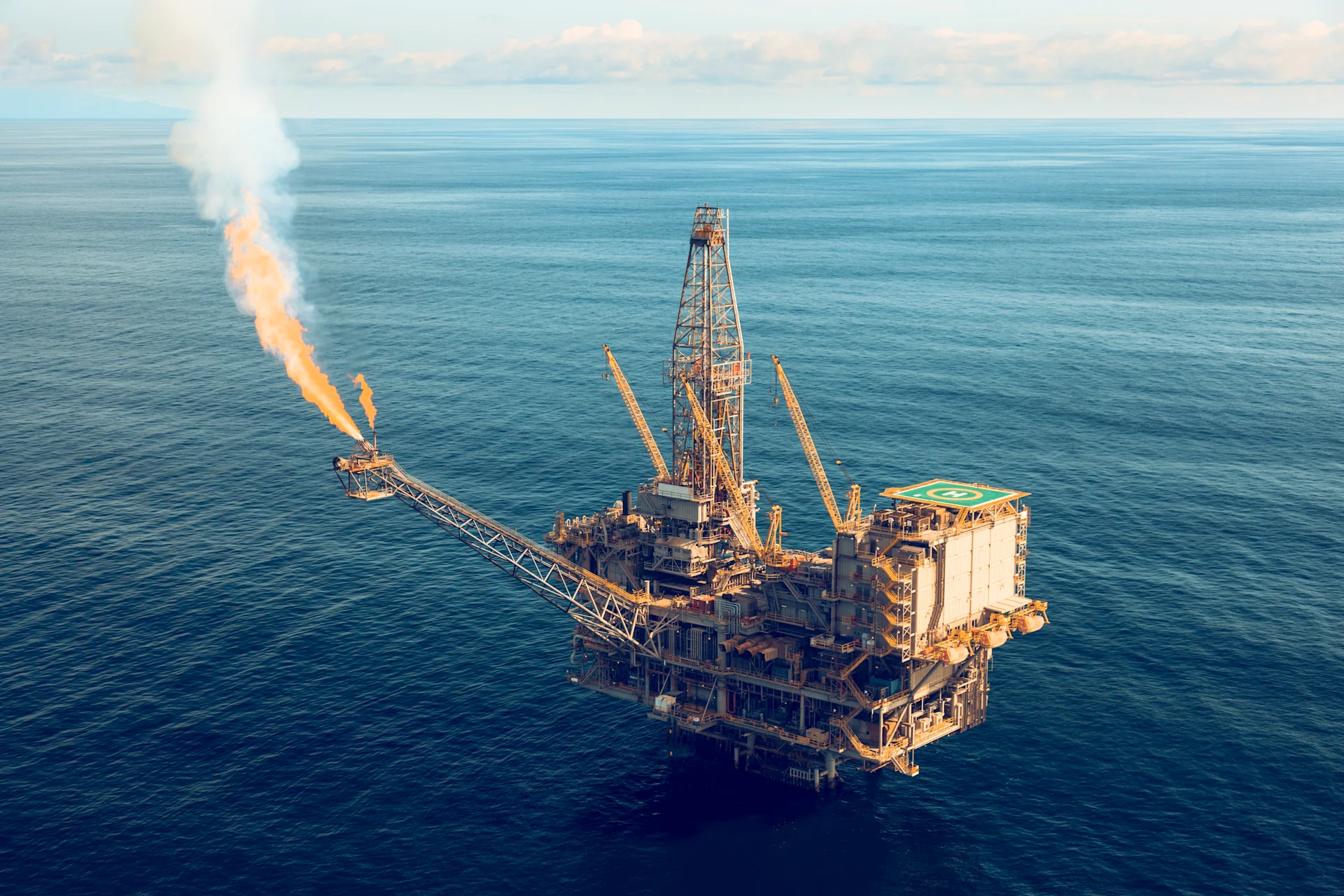 aerial photo of a massive oil rig in a calm, blue ocean.