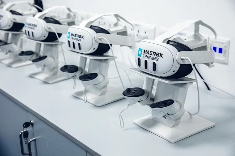 virtual reality (VR) headsets branded with "Maersk Training," neatly arranged on stands.