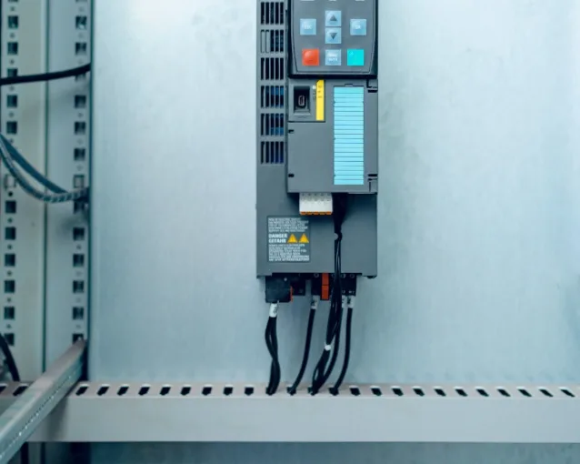 Kabelkanal med slidser monteret på væg med ledninger der føres til elektrisk apparat