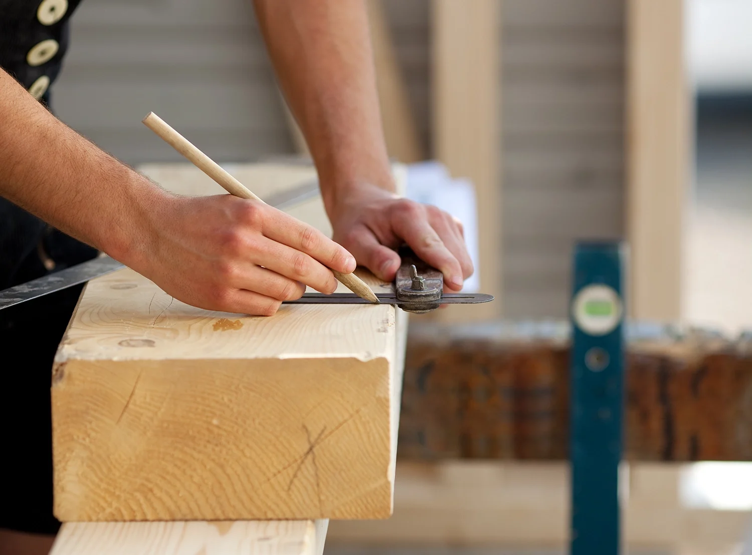 Ein Zimmermann der einen Holzbalken anzeichnet