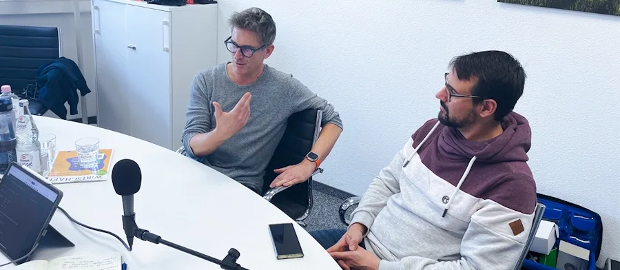 Jürgen Steiner und Jan Wilhelm sitzen zusammen im Podcast Raum und unterhalten sich