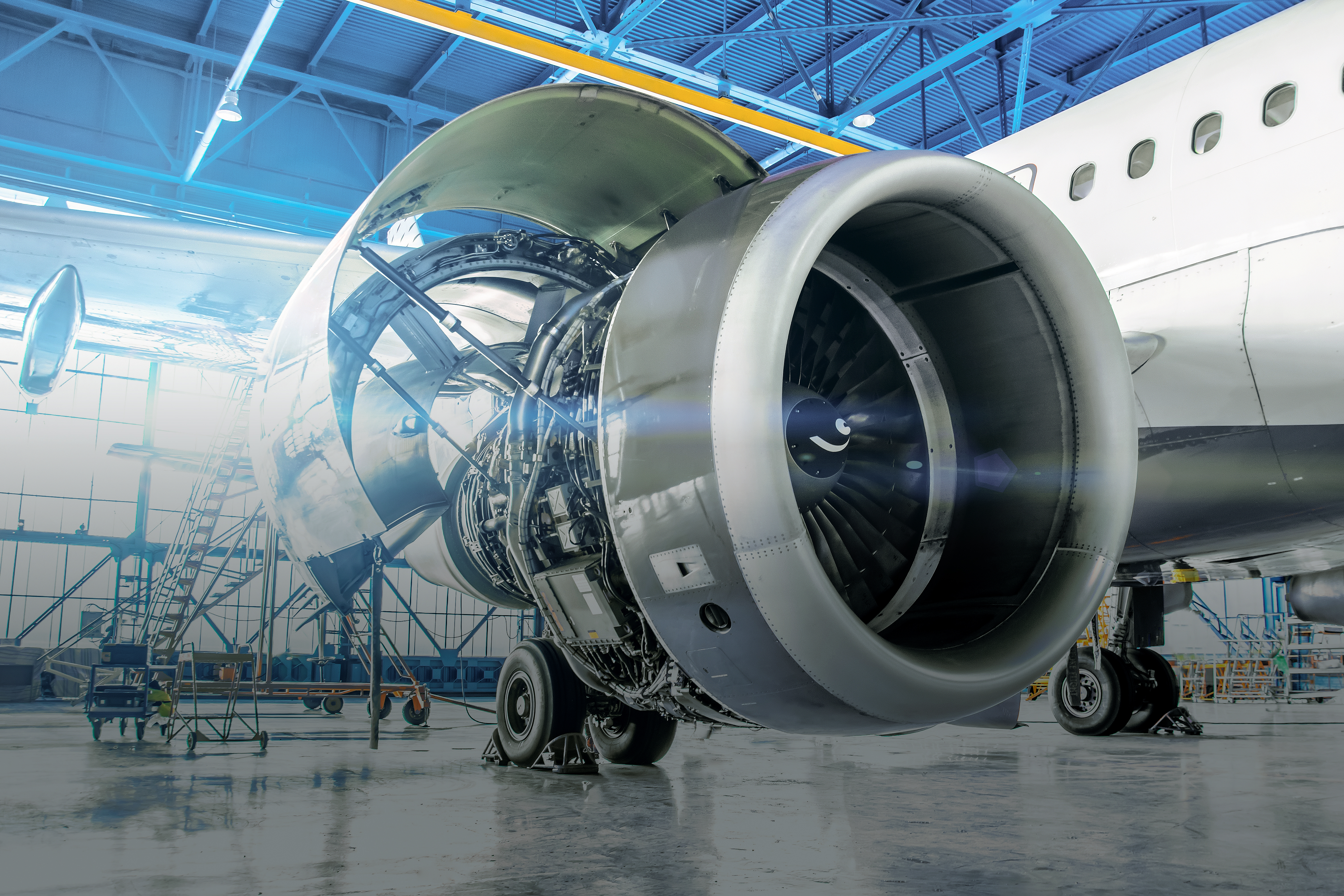 
Eine Nahaufnahme eines Flugzeugmotors in einem Hangar mit blauen Wänden, die seine mechanischen Merkmale hervorhebt.