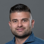 Portrait von Jan Oelmeier mit dunklem Haar, seriöses Lächeln, Business-Kleidung.