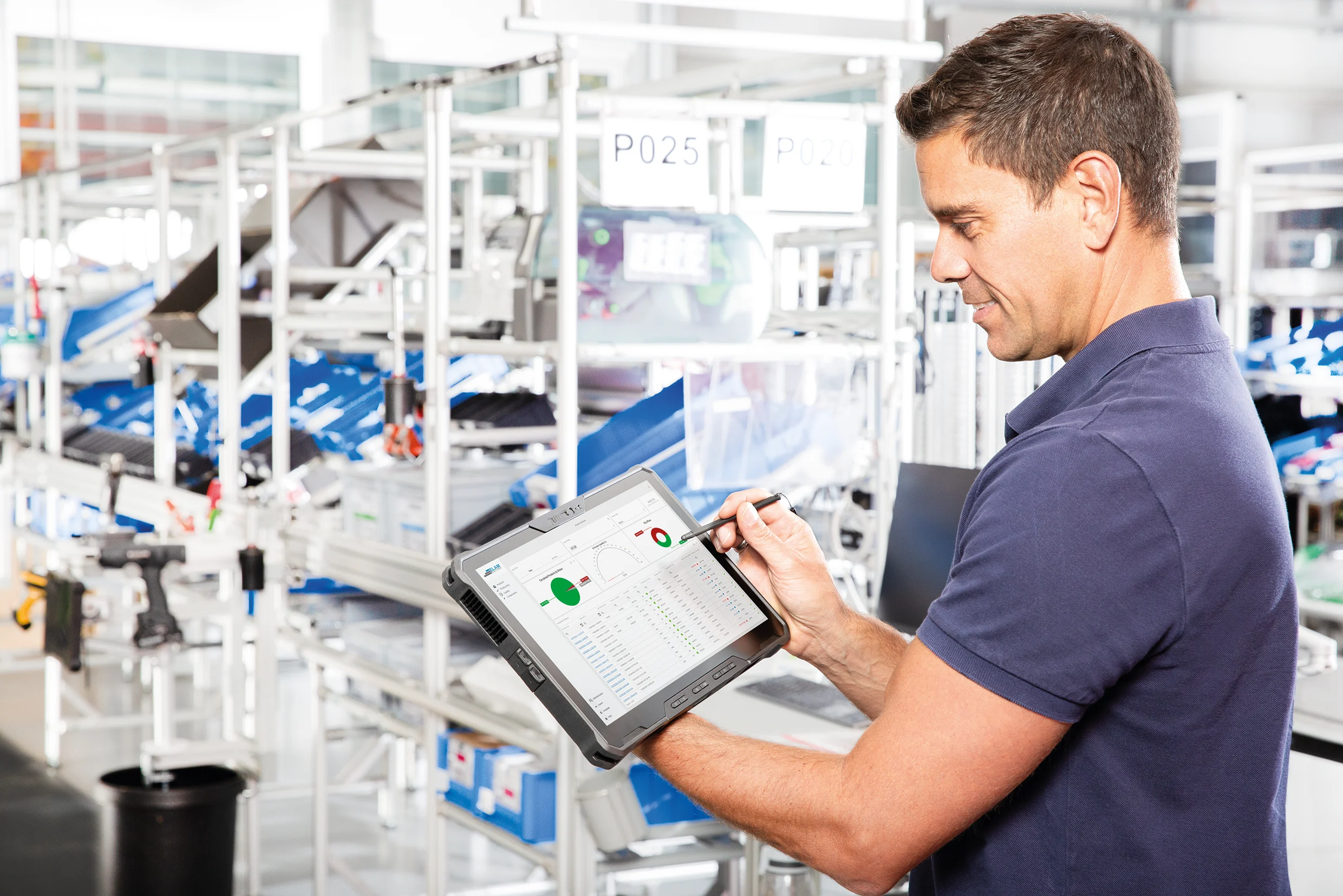 
Smart Factory Assembly Guy med tablet i hænderne kigger på dashboardet med realtidsdata