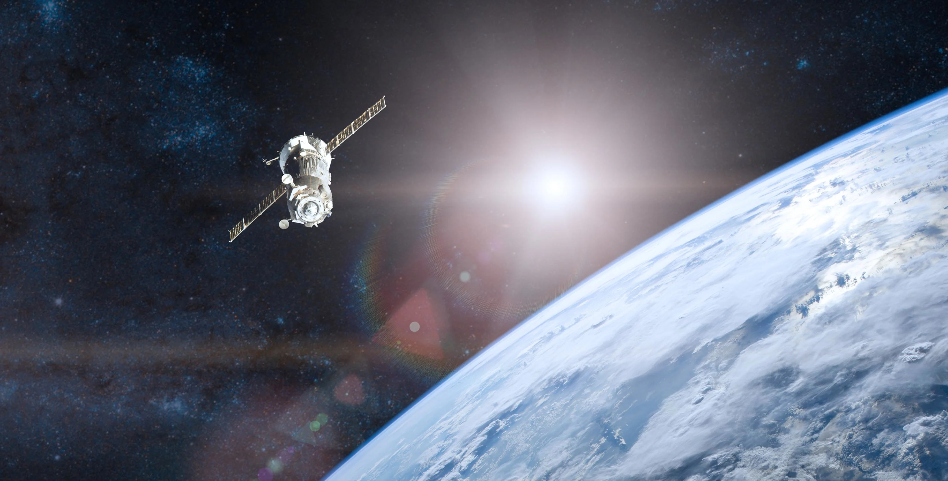 Un satellite orbita sopra la Terra con nuvole visibili, sullo sfondo dello spazio stellato e un sole luminoso in lontananza.