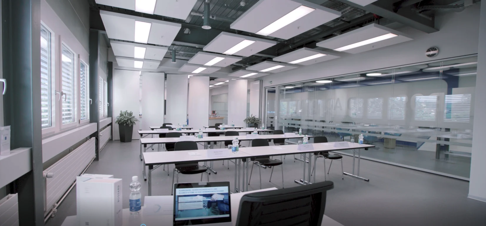 Klassenzimmer mit Tischen und Stühlen, die vor einem Fenster angeordnet sind und Licht spenden.